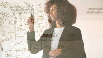 Focused young businesswomen writing on virtual board