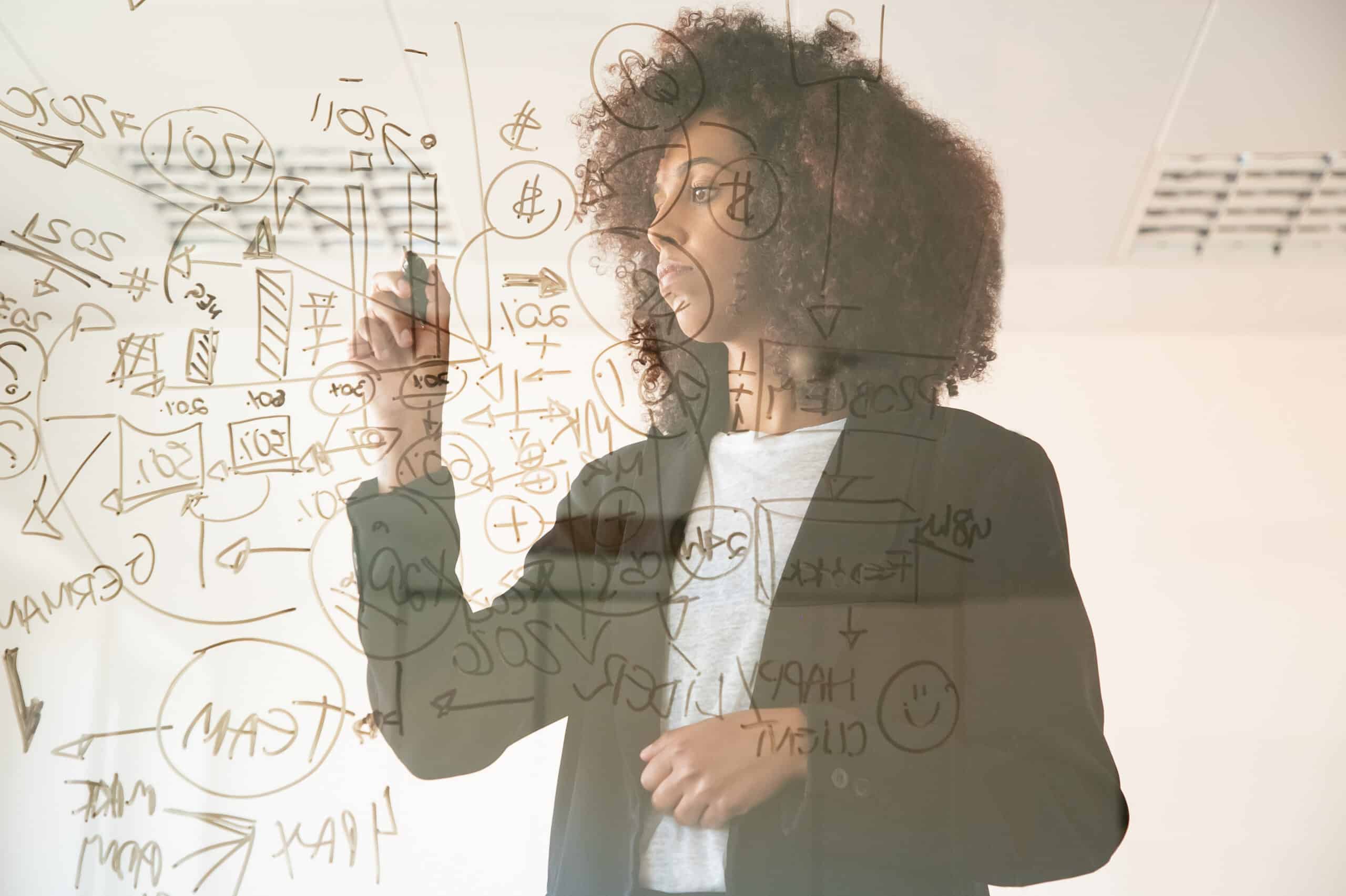 Focused young businesswomen writing on virtual board